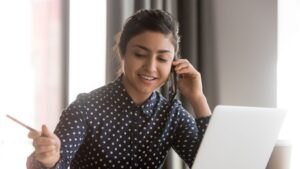 ''Une dame regarde son ordinateur et parle au téléphone. Elle utilise la téléphonie IP BICOM''